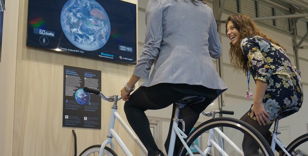 Participants pédalant sur des vélos générateurs pour alimenter un écran diffusant un jeu vidéo, illustrant l'animation interactive de Ludik Énergie.