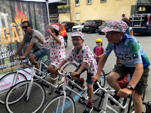 Animation Tour de France Vélo Battle, sur un stand événementiel, avec une famille qui s’affronte dans un duel sportif à vélo en portant le maillot à pois.
