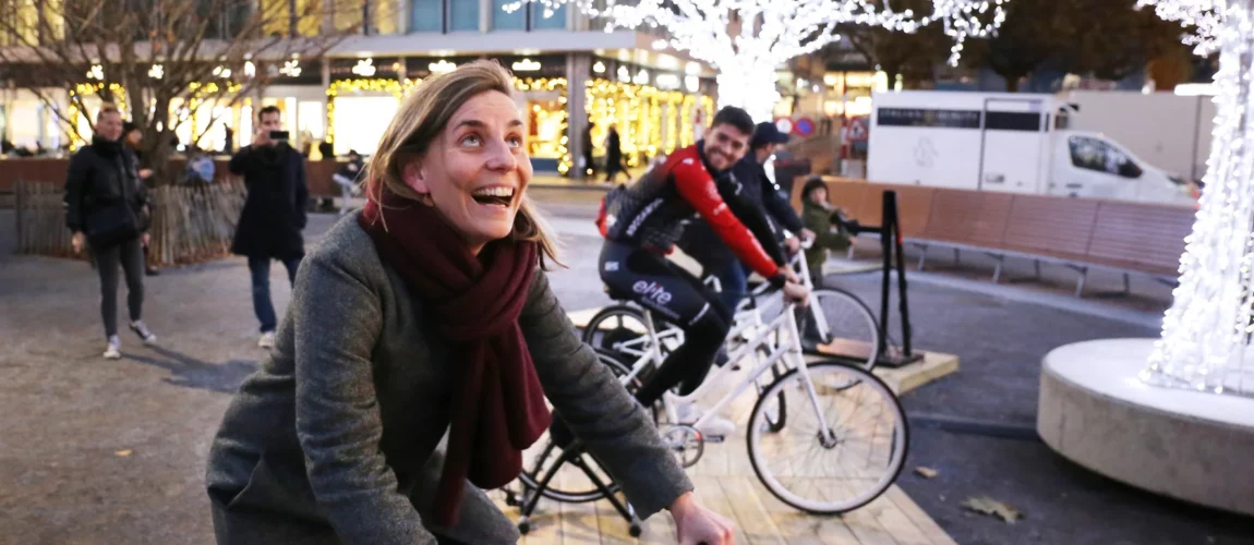 Une femme et un homme qui participent à une animation pour marché de Noël sur une place en plein centre-ville.