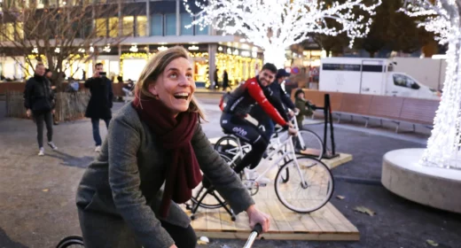 Une femme et un homme qui participent à une animation pour marché de Noël sur une place en plein centre-ville.