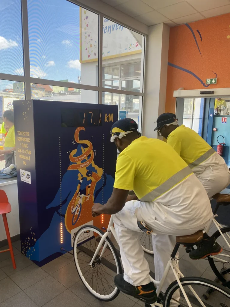 Deux collaborateurs qui pédalent sur un vélo pour tenter de remporter le challenge Vélo Battle du team building green organisé par leur entreprise.