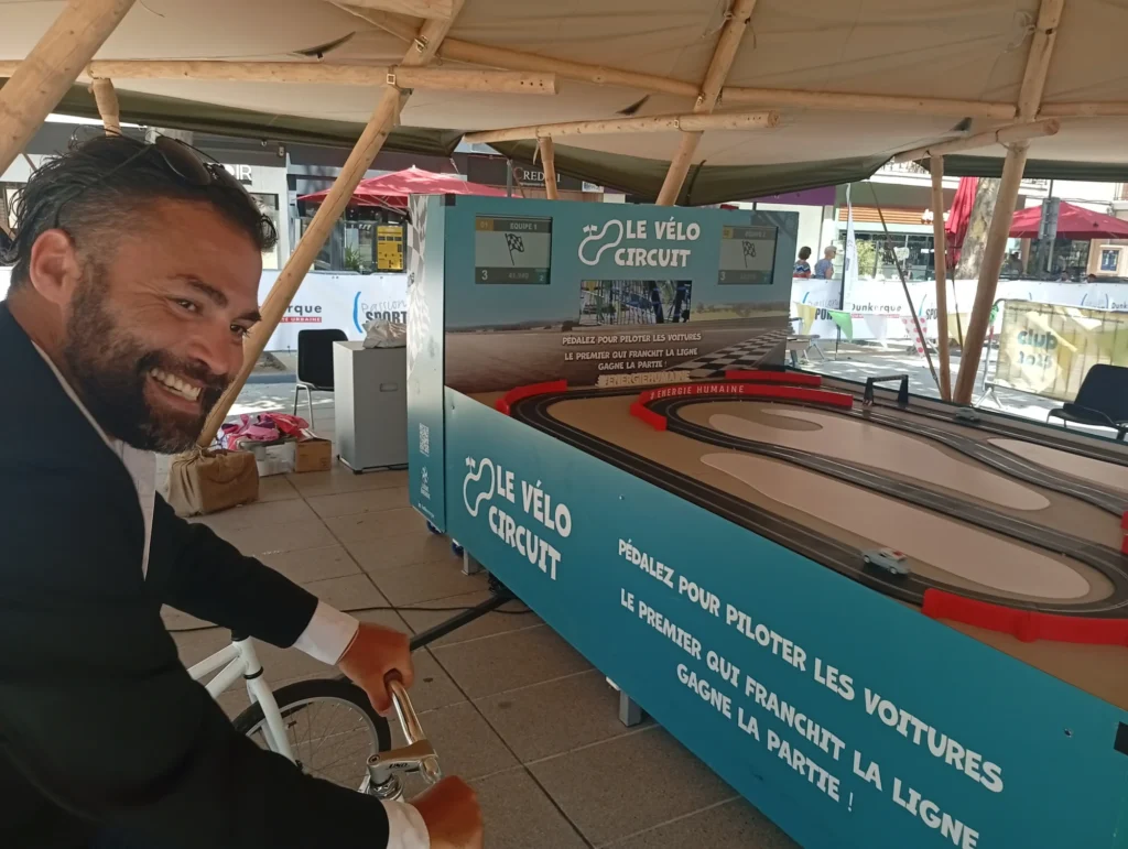 Participant installé sur l’animation Vélo Circuit qui pédale pour faire avancer sa voiture miniature sur le circuit, au cours d’un team building green.
