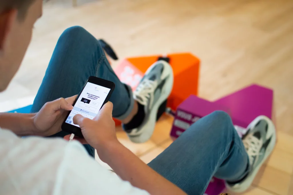 Jeune homme qui recharge son téléphone sur une borne de recharge à pédales, lors de sa pause sur son lieu de travail.