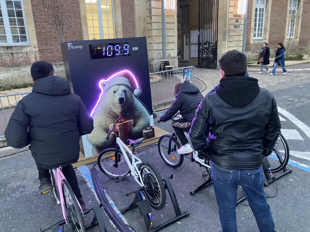 Deux participants qui s’affrontent en duel sur un stand vélo battle au cours d’un team building, sur le thème de Noël.