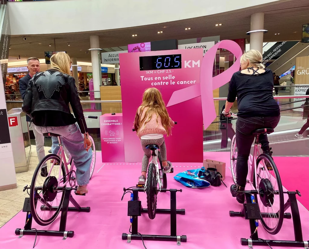 Deux femmes et une fille qui participent à une course solidaire à vélo pour récolter des dons pour octobre rose.