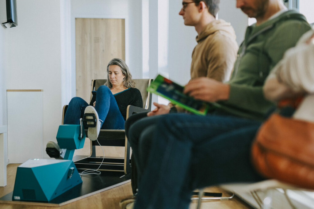 Une salariée d’une entreprise dans une salle de pause avec ses collègues, qui utilise un pédalier de recharge pour charger son téléphone professionnel.