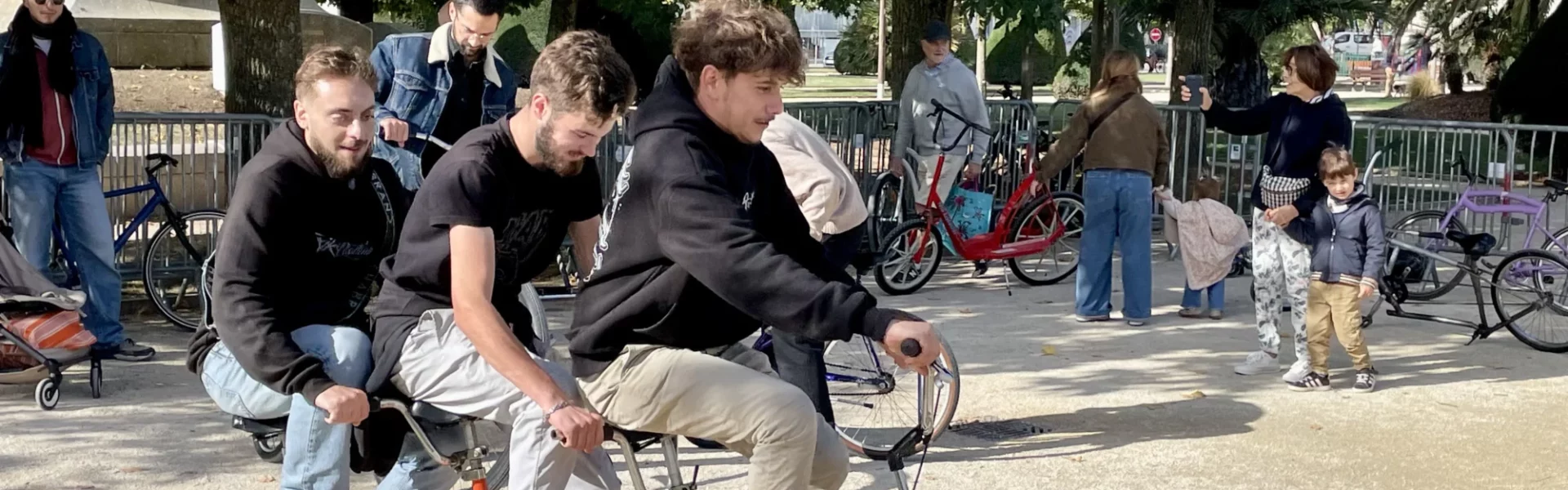 3 jeunes s'amusent à essayer un vélo insolite lors d'une animation vélo fun