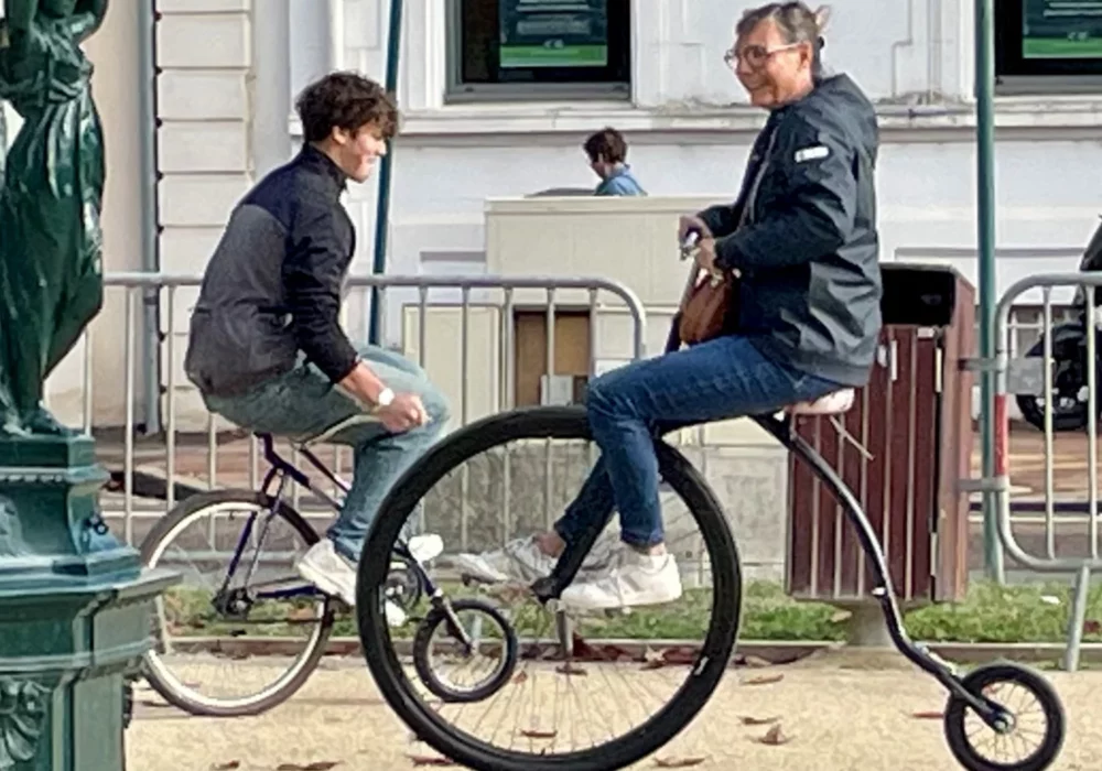 Un adolescent et un adulte s'amusent sur deux vélos insolites sur la place publique